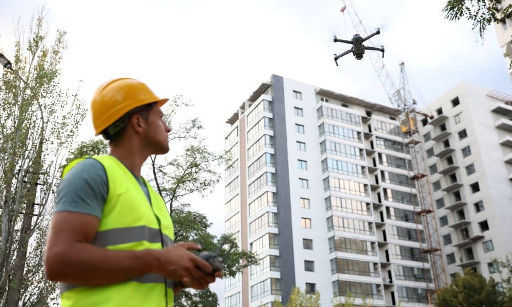 Drone surveyor operating a drone near tall buildings during aerial surveying, showing GPS interference risk in urban construction sites