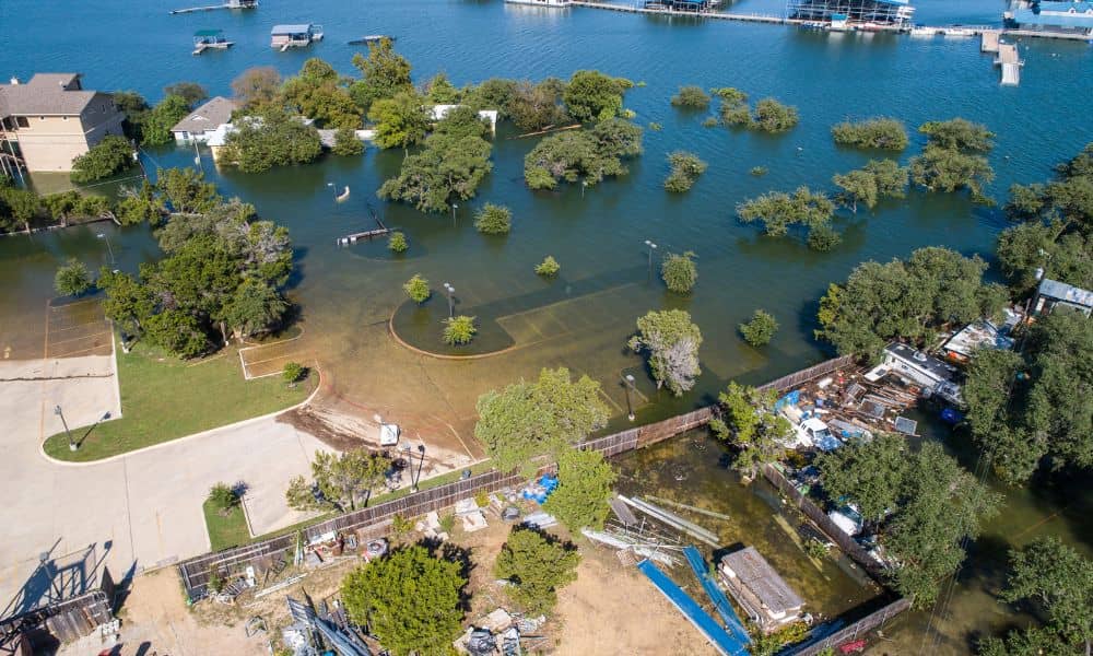Aerial view of a flooded neighborhood showing rising water around homes and trees, illustrating the risks of outdated FEMA flood maps and the need for a flood elevation certificate