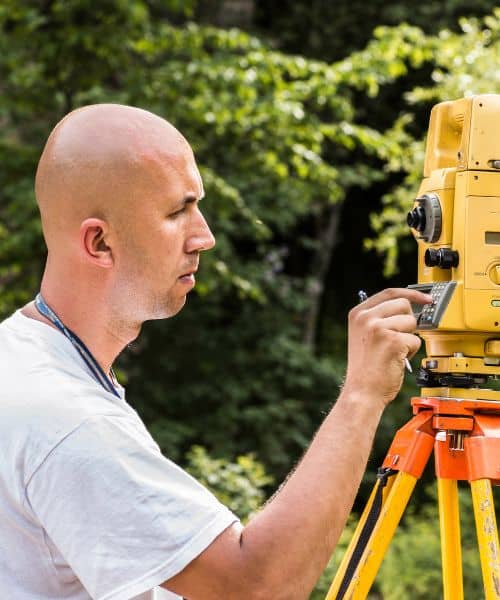 A land surveyor measuring ground elevation for a flood elevation certificate