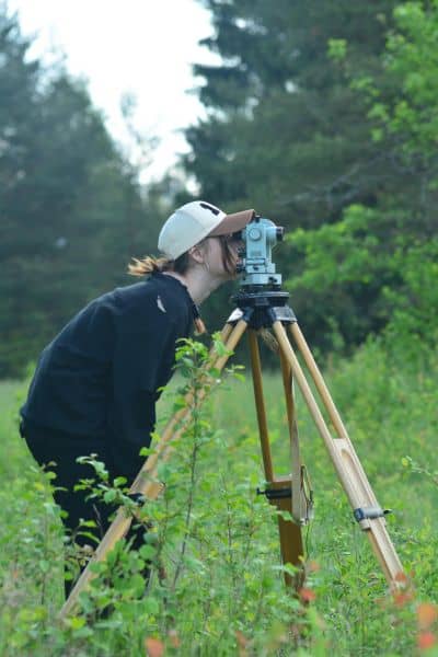 Surveyor using a total station during a boundary survey to measure property lines in the field
