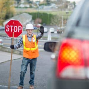 Flagger stopping traffic work zone - ALTA SURVEY Dallas Road flagger stopping cars in a work zone, showing a disruption that a traffic study should account for when evaluating near-miss risk