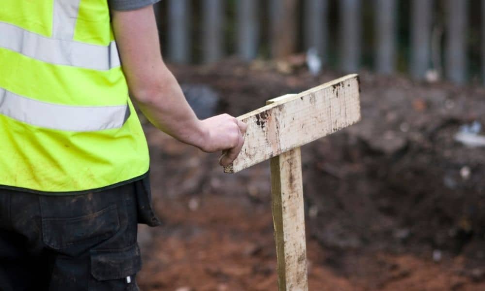 Licensed land surveyor marking a property boundary during a property line survey to confirm legal ownership