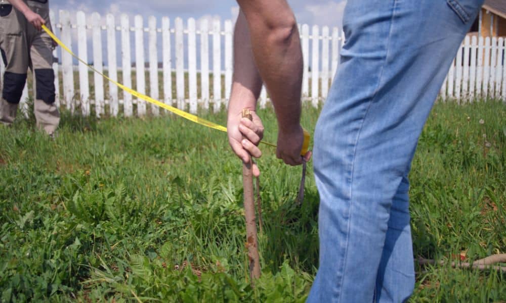 Surveyor measuring and marking a fence line to verify boundary survey cost and property limit